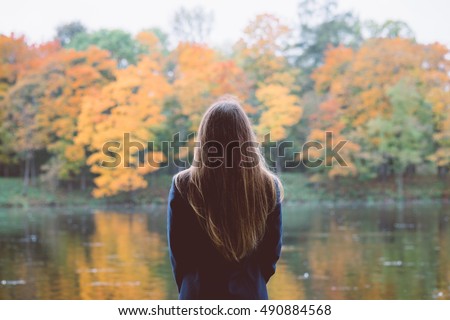 Outdoor autumn landscape. Orange autumn portrait. Autumn girl standing backwards. Autumn lake. Autumn forest colors. Watching autumn nature. Orange autumn tranquility. Woman watching autumn outdoor