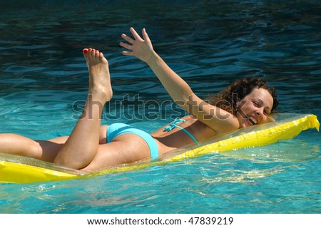 Young woman swimming on mattress in water pool