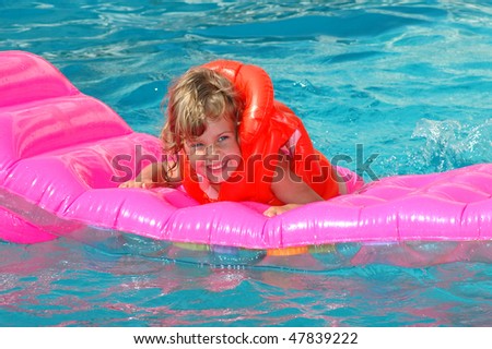 The little girl swimming on an inflatable mattress in pool