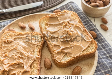 Peanut butter  on wooden plate with nuts on wooden table