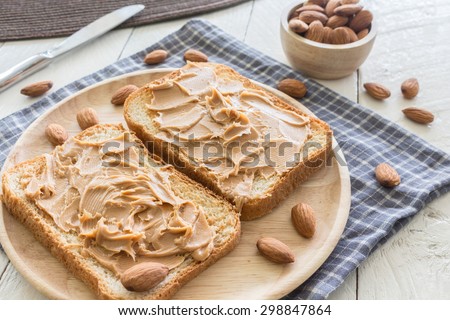 Peanut butter  on wooden plate with nuts on wooden table