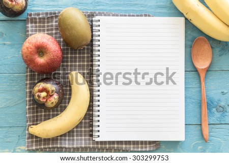 Recipe book with fruits on wooden background
