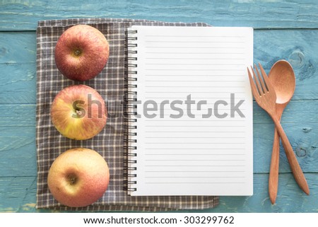 Recipe book with apple  on wooden background
