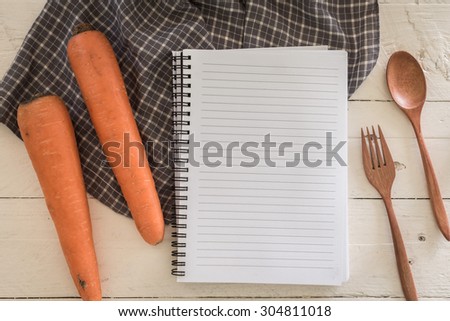 Recipe book with carrot  on wooden background