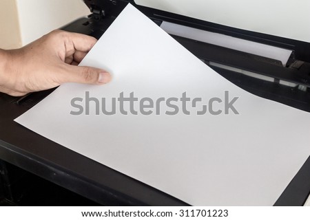 Hand holding paper sheets into printer tray