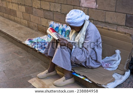 Aswan, Egypt - January 2010: A local poor man with turban reading the newspaper in the city market