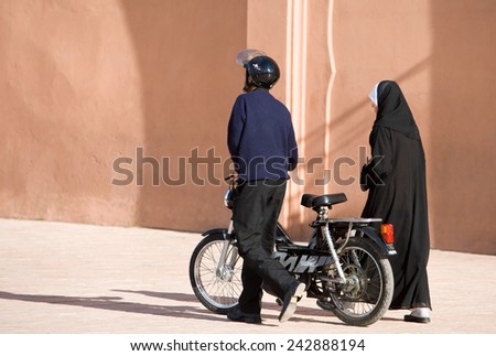 Marrakesh, Morocco - March 2006: A young couple with motorcycle walking in the old city center