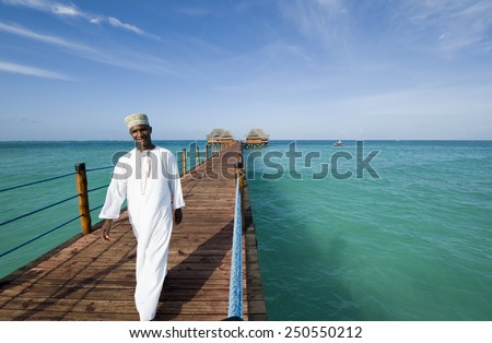 Bwejuu, Zanzibar - February 28 2008: A waiter walking on  a wharf with bungalows of an holiday village on the eastern coast