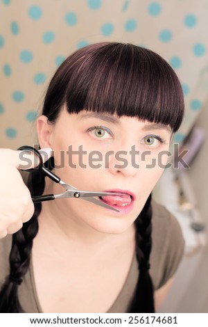 Young woman cutting tongue with scissors