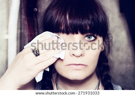 Horror concept: Woman removing eye with make up remover. Wiping face clean.