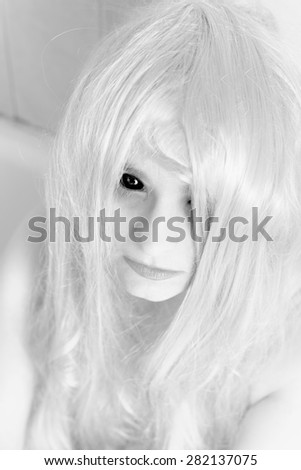 White ghost like girl with black eyes sitting in a bathtub. Monochrome photo, horror or Halloween concept.
