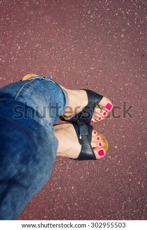 Woman\'s legs in jeans and black sandals