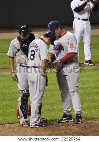 BALTIMORE - MAY 1: Daisuke Matsuzaka of the Boston Red Sox has trouble before speaking with coach John Farrell and Victor Martinez during a game at Camden Yards on May 1, 2010 in Baltimore, Maryland
