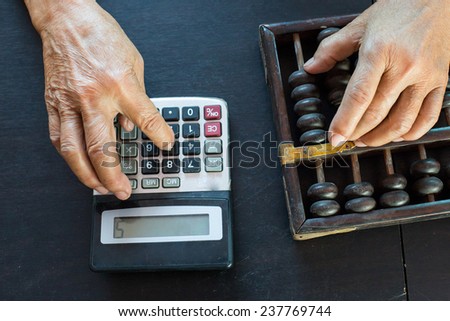 Old asian woman hands accounting with the old abacus and calculater