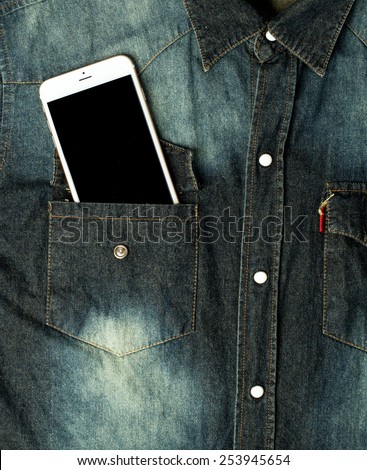 white smart phone in pocket with black screen. Lying on shirt jeans