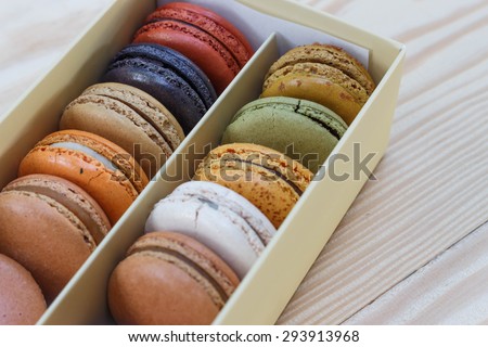 traditional french sweet dessert colorful delicious macarons in a rows in a box on wood background focus on red and green