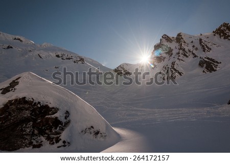 Winter landscape with sun moving past mountain ridge