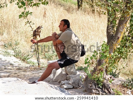 Ukraine, Bakhchisaray - September 06, 2011: Man and tame bird of prey on the trail in Calais