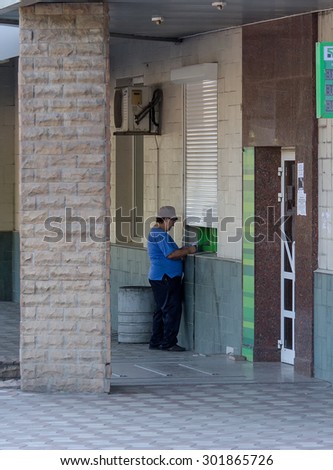 Makeevka, Ukraine - July 30, 2015: Elderly woman near an ATM at the branch of the non-working commercial bank nationalized by the authorities of the People\'s Republic of Donetsk