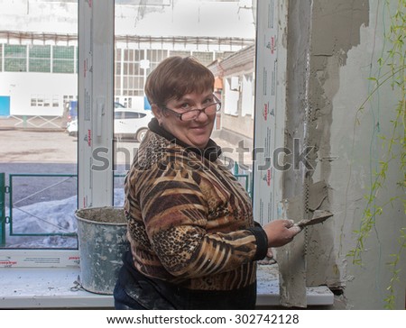 Ugledar, Ukraine - February 20, 2013: Female plasterer doing slopes in the economic building mines of South Donbass 1