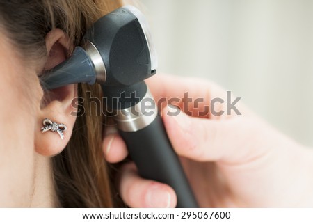 young woman doctor monitors the patient\'s ear with otoscope