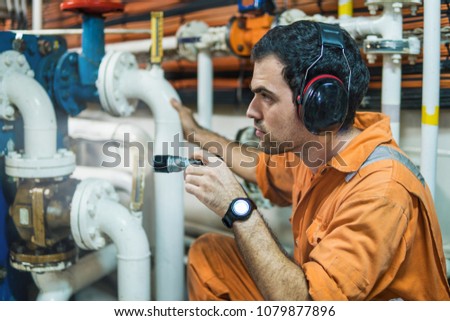 Marine engineer inspecting ship\'s engine with torchlight in engine control room ECR. Seamen\'s work.