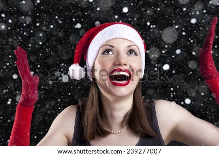 Christmas smiling woman in Santa hat and red gloves with snowflakes on a black background