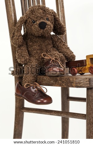Cute soft toy puppy sitting on a chair in old leather shoes