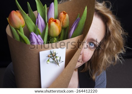 Beauty woman model with spring flower bouquet. Beautiful girl with a bouquet of colorful tulip flowers. Happy surprised woman model smelling flowers. Mother\'s Day. spring