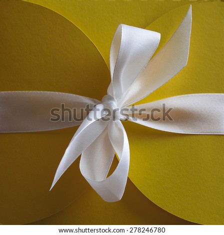 Brilliant white satin ribbon on a yellow background