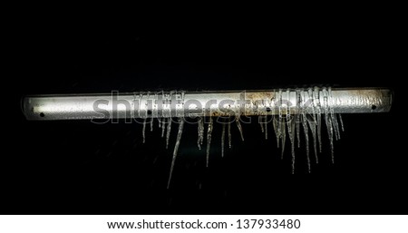 Icicles hanging from a frozen fluorescent light tube.