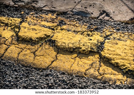 Old, weathered yellow road marking in need of repair.