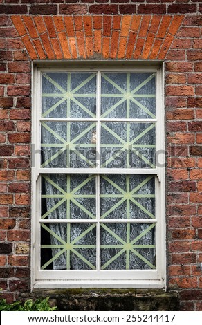 Old fashioned WW2  era window with net curtains and tape to minimise bomb damage.