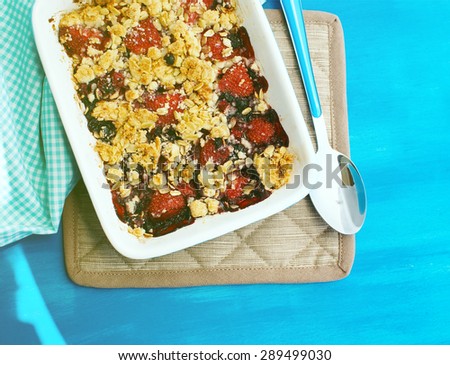 Crumble with strawberries, red currants, blueberries and blackberries with crumb made of powdered sugar, almonds, flour and oatmeal flakes