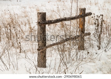 fence at a  dirt road\'s edge surrounded by dry bushes in italian mountains