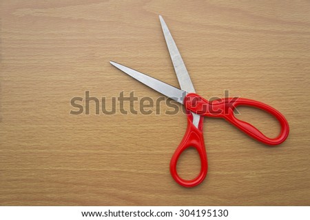 red scissors on wooden background
