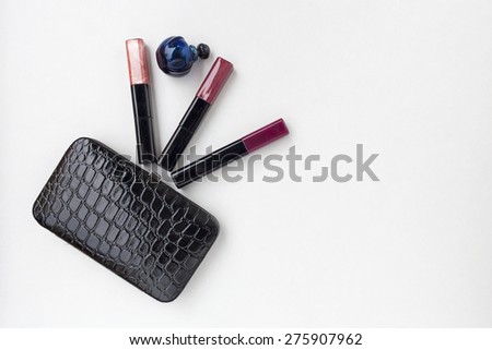 Black leather bag, blue perfume bottle, blue perfume bottle and color lips gloss on white background