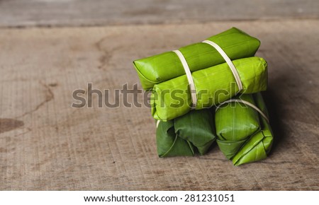 Banana with sticky rice in banana leaf with space on wooden floor