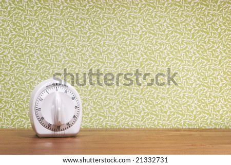 A timer sits on a wood surface against a patterned green background.