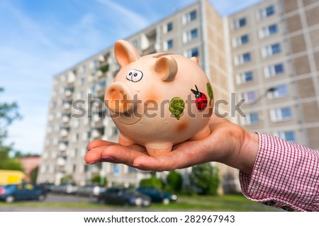 All savings money from pink ceramic piggy bank to pay for the dream home on blurred background