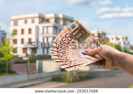 Property buyer holding euro banknotes and buying beautiful house from real estate agencies on blurred background