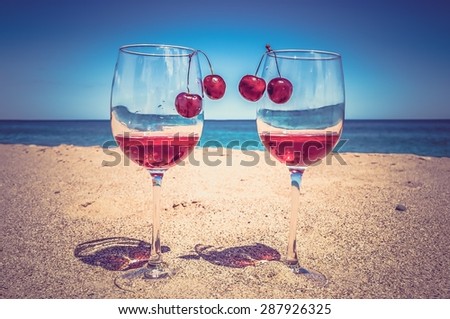 Glasses of wine and cherries on the beach, romance near the sea - retro and vintage style