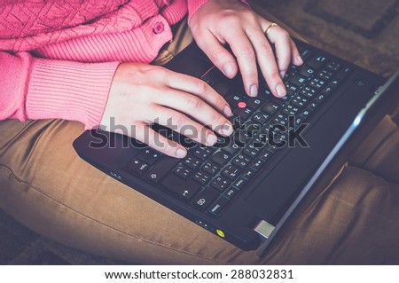 Young woman using a laptop and sitting on the floor in a living room - retro and vintage style