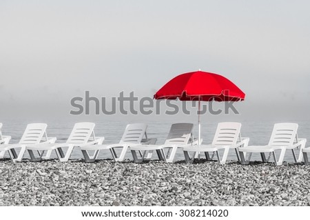 Red sun umbrella and plastic beach beds, black and white concept