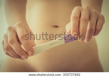 Pregnant woman holding positive pregnancy test in the bedroom