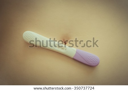 Pregnant woman and positive pregnancy test on belly