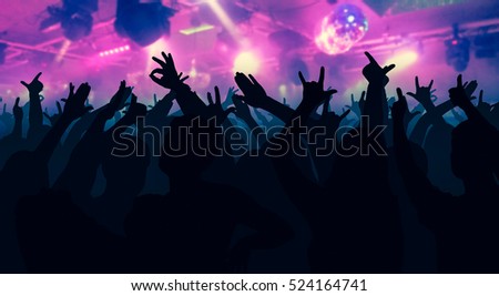 Silhouettes of dancing people in club in front of bright stage lights - disco concept
