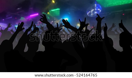 Silhouettes of concert crowd with hands raised at a music festival in nightclub - disco concept