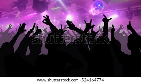 Silhouettes of dancing people in club in front of bright stage lights - disco concept