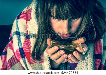 Sick young woman with fever drinking cup of warm tea - flu concept - retro style